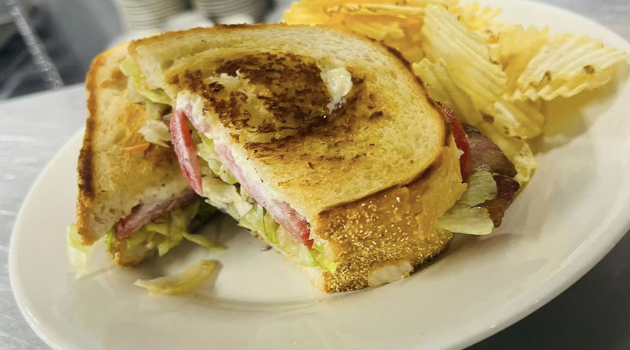 Toasted sandwich from 1st St. Cafe in Leechburg, PA, with lettuce, tomato and meat, served with chips.